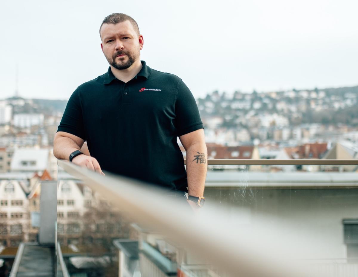 Mann steht auf Balkon und symbolisiert transparente Arbeitsweise im Energievertrieb.