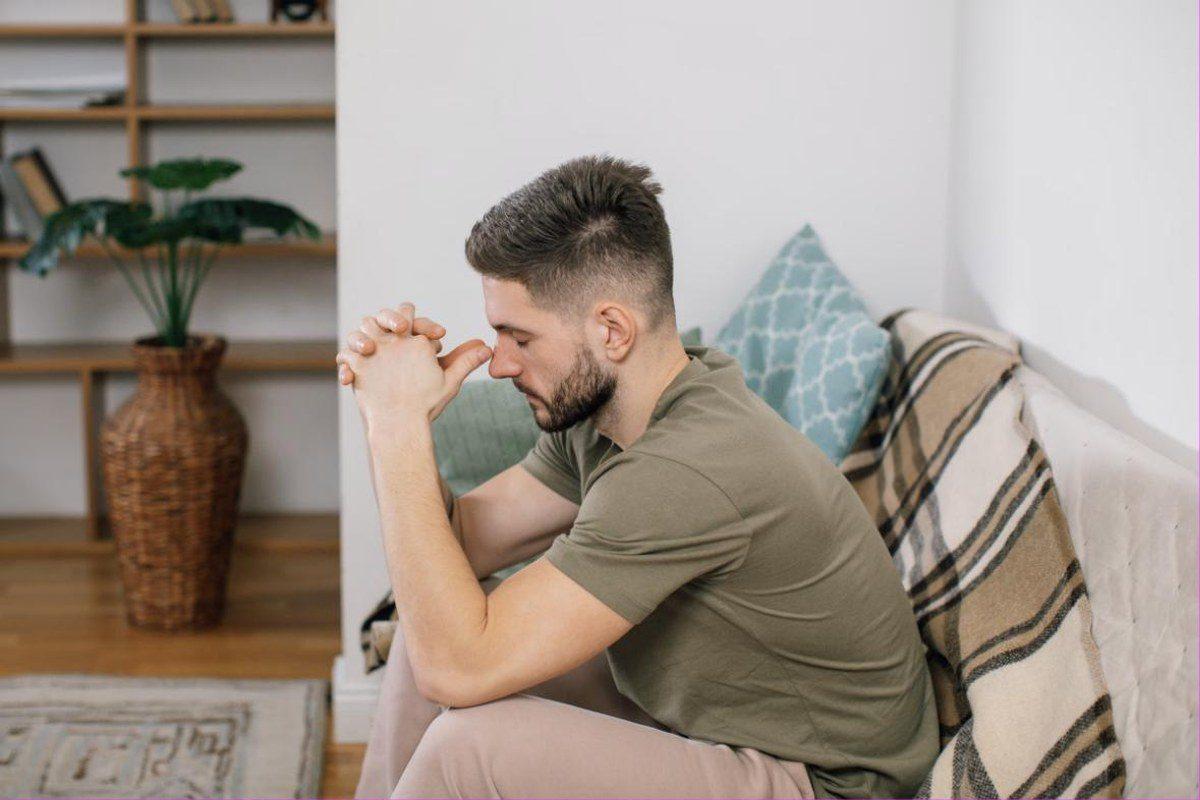 Nachdenklicher Mann sitzt auf einer Couch und reflektiert die Ursachen seines Schwangerschaftsfetischs.