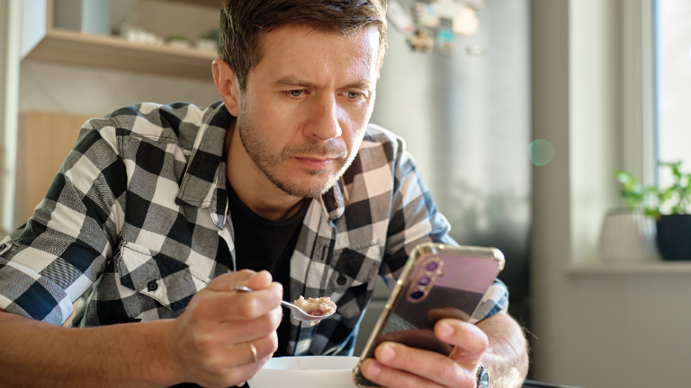 Mann mit Smartphone, der über zwanghafte Masturbation nachdenkt.