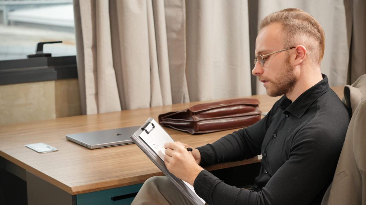 Ein Mann sitzt in einem Büro und liest einen Notizblock zum Thema Trans-Fetisch loswerden.