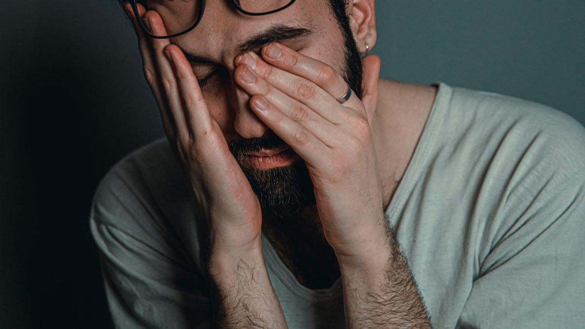 Ein Mann mit Händen im Gesicht zeigt Anzeichen von Stress in Bezug auf Pornosucht.