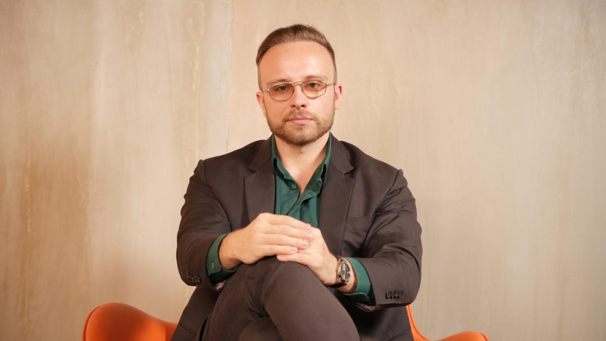 Mann in Anzug sitzt auf einem Sessel und reflektiert über Findom loswerden.