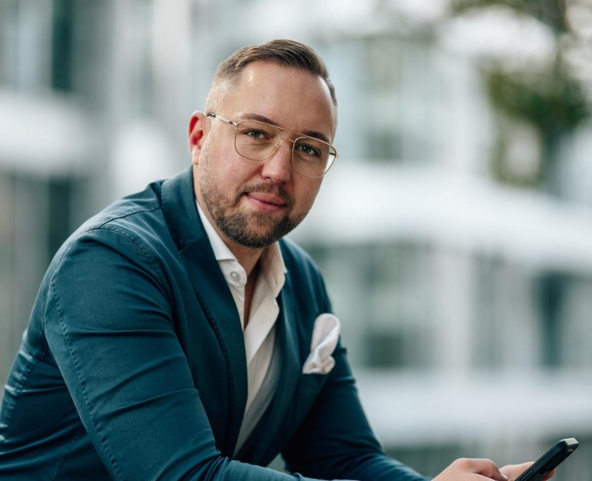 Ein mannlicher geschäftsmann mit Smartphone sitzt und spricht über Steuern sparen für Immobilienvermögen.