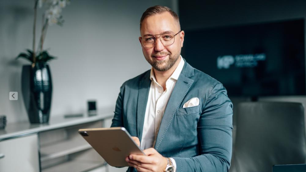 Mann in Anzug mit Tablet, der Steuern sparen und Immobilienvermögen diskutiert.