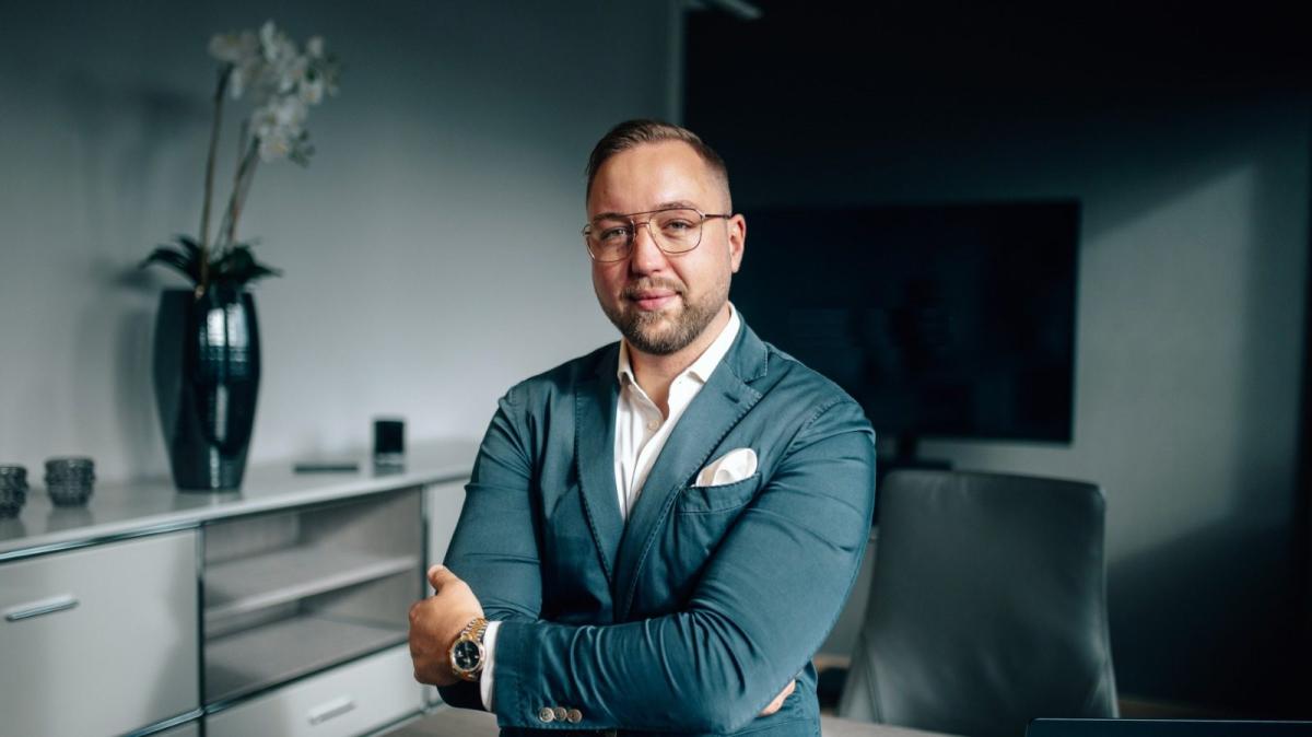 Ein Mann in Anzug steht im Büro und erläutert den Unterschied zwischen Vermieter und Investor.