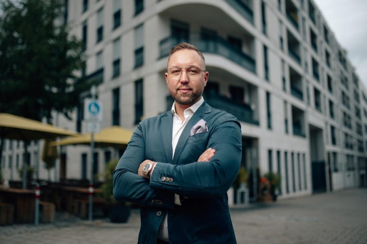 Mann in Anzug vor modernem Gebäude, symbolisiert Bestandsimmobilien als Kapitalanlage.
