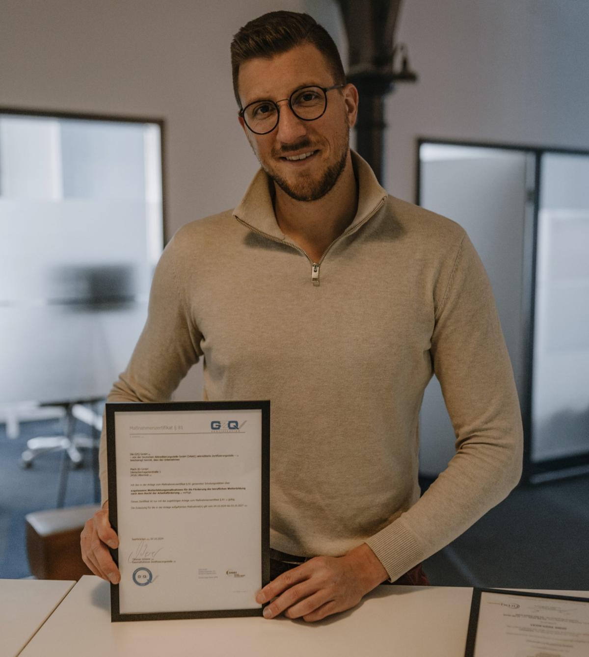 Ein Mann hält stolz ein Zertifikat für digitale Qualitätsstandards in der Hand.