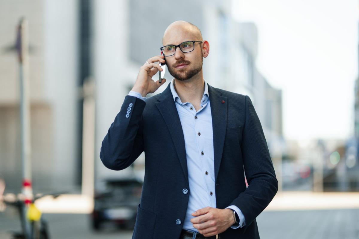 Ein Mann in Anzug führt ein Telefonat für Kaltakquise für Sachverständige.