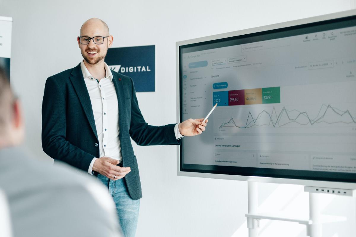 Ein Präsentator zeigt Statistiken zur Reduzierung von Auftragsschwankungen.