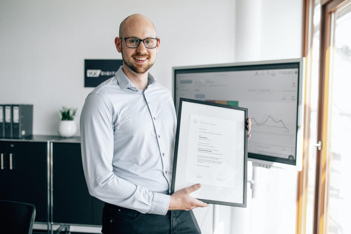 Ein Sachverständiger hält stolz sein DIN ISO 17024 Zertifikat in der Hand.