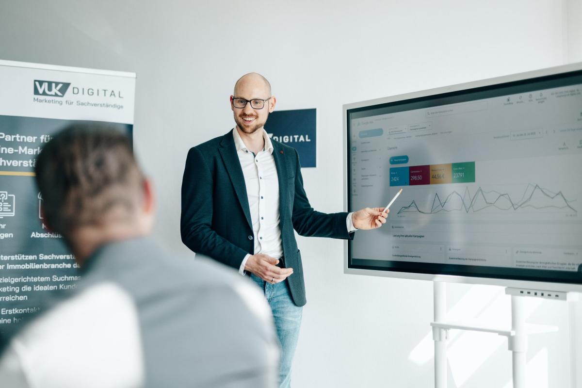 Ein Präsentierer erklärt in einer Google Ads Kampagne an einem Bildschirm Grafiken.