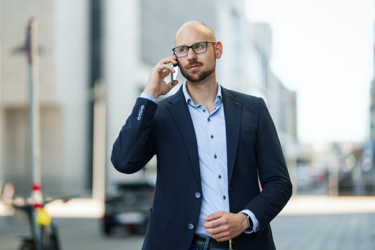 Mann im Anzug bei einem Telefonat, Schlüssel für den Netzwerkaufbau für Sachverständige.