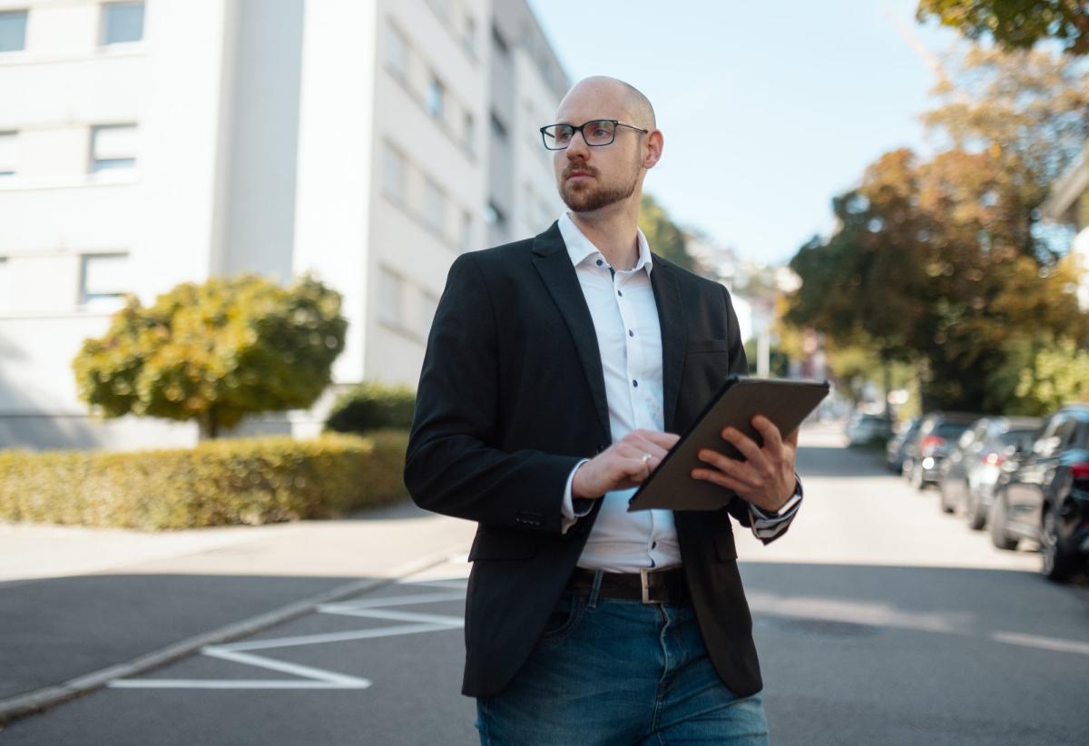 Mann mit Tablet auf der Straße, symbolisiert Kundenpipeline für Gutachter.