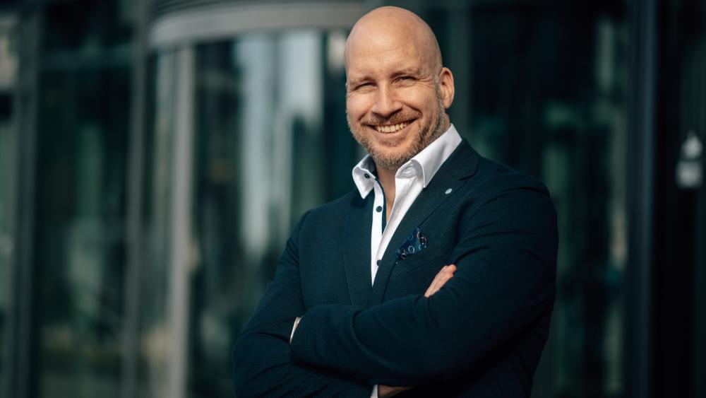 Portrait eines Mannes, der freundlich lächelt und Diversifikation im KI-Boom betont.