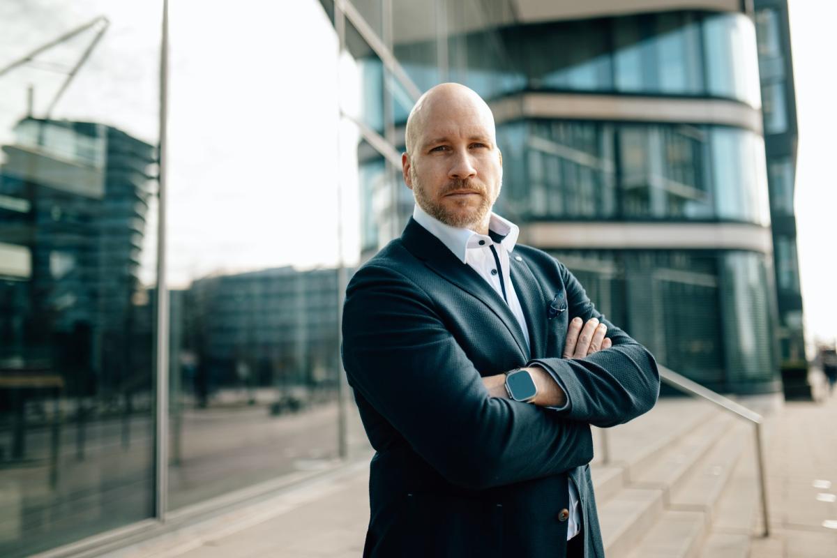 Ein Geschäftsmann steht vor einem modernen Gebäude und verkörpert den Fokus auf private Märkte.