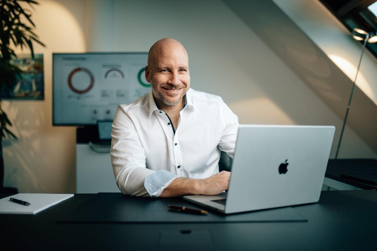 Ein lächelnder Mann arbeitet am Laptop mit Diagrammen zum SpaceX Börsengang.