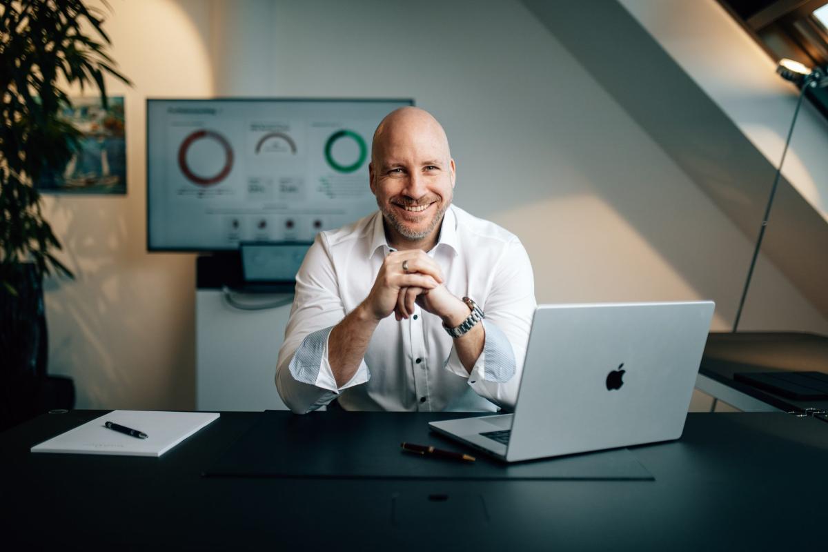 Ein beratender Mitarbeiter mit Laptop erklärt die Fehler beim Investieren über Neobroker.