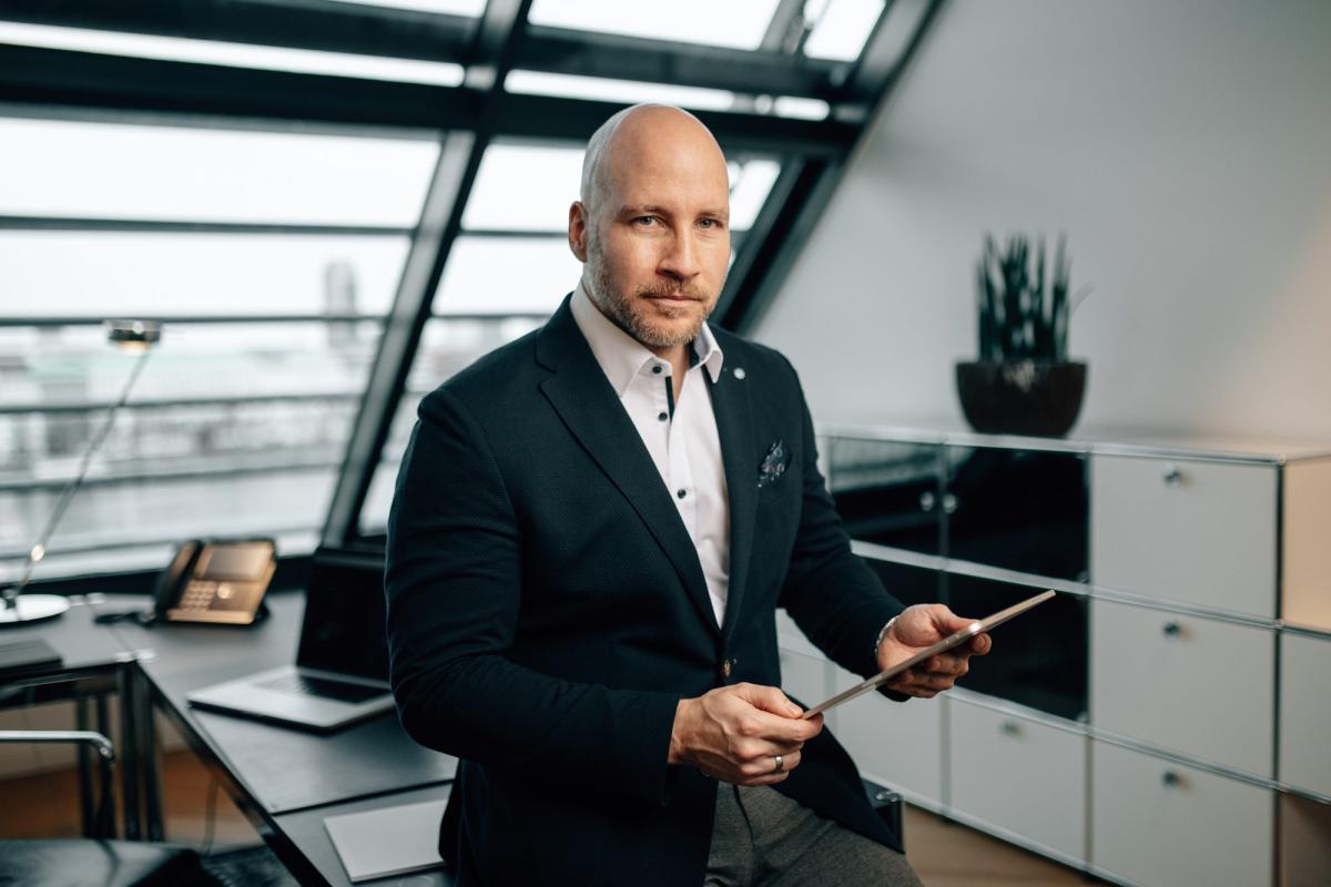 Mann mit Tablet in einem modernen Büro, Thema Denkfehler beim Investieren.