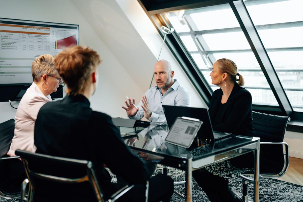 Eine Besprechung zur privaten Krankenversicherung im Alter mit vier Personen in einem modernen Büro.