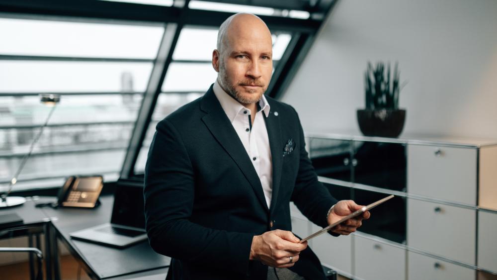 Mann im Anzug hält ein Tablet, um über private Krankenversicherung im Alter zu sprechen.