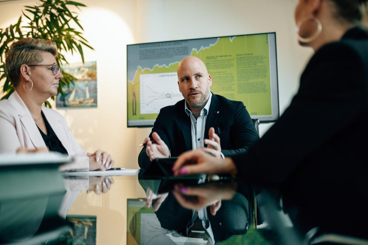 Altersvorsorge Unternehmer im Beratungsgespräch: Ein Mann erläutert einer Frau am Schreibtisch Unterlagen.
