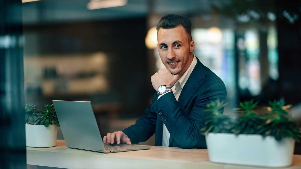 Ein Mann sitzt am Laptop und ist konzentriert, als er über den besten Anbieter für eine Trading-Ausbildung nachdenkt.