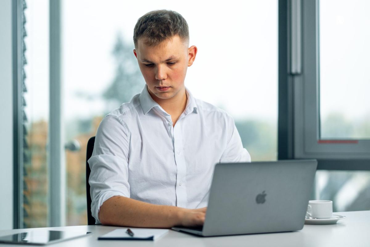 Ein junger Mann arbeitet konzentriert an seinem Laptop während der kostenlosen Werbetext-Beratung.
