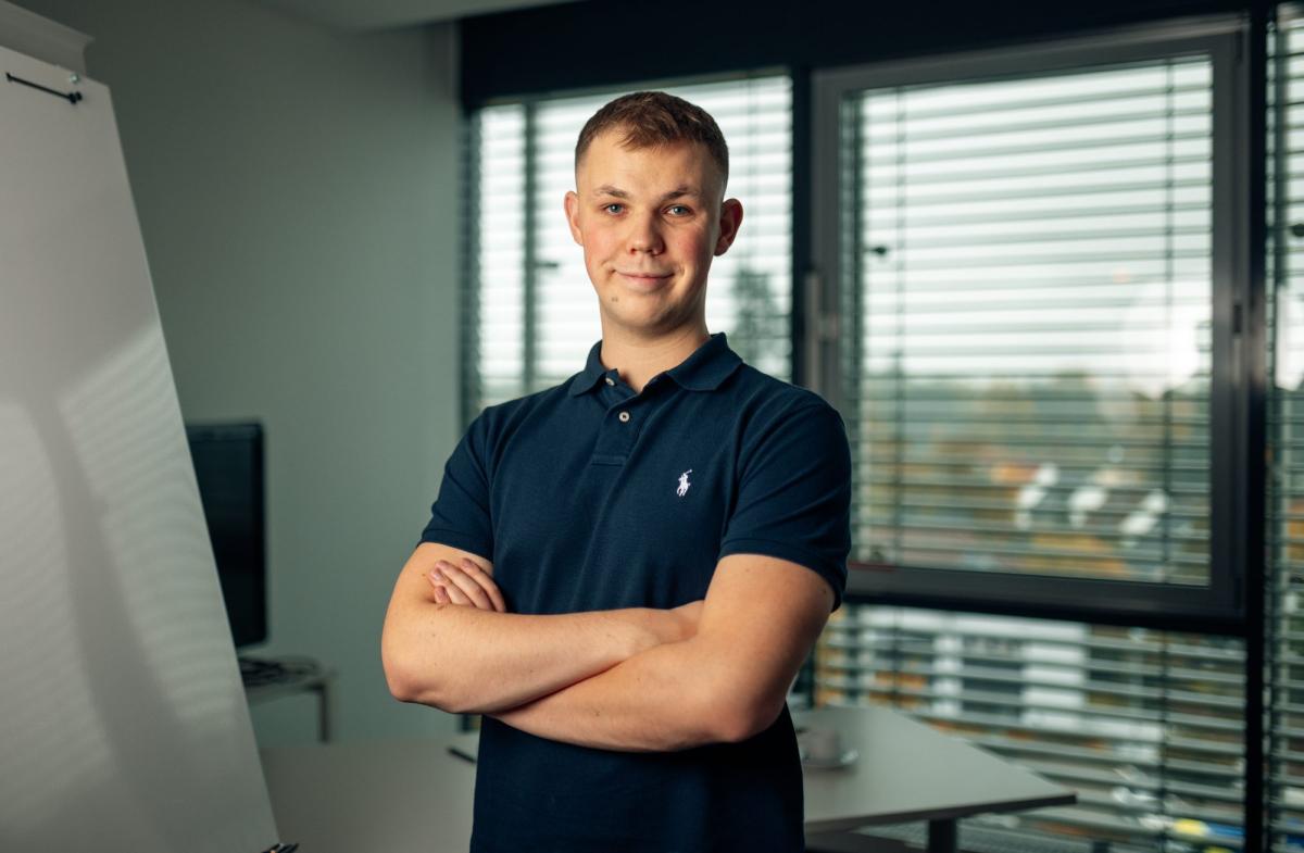 Mann in Polohemd steht im Büro, präsentiert Webdesign-Agentur Extras.
