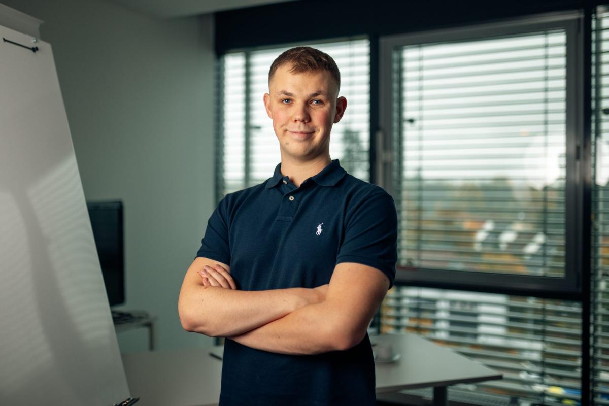 Junger Mann steht in einem Büro und spricht über DMC-Report Landingpage.