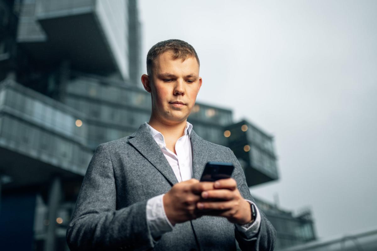 Mann nutzt sein Handy und hebt sich unvergleichbar als Coach hervor.