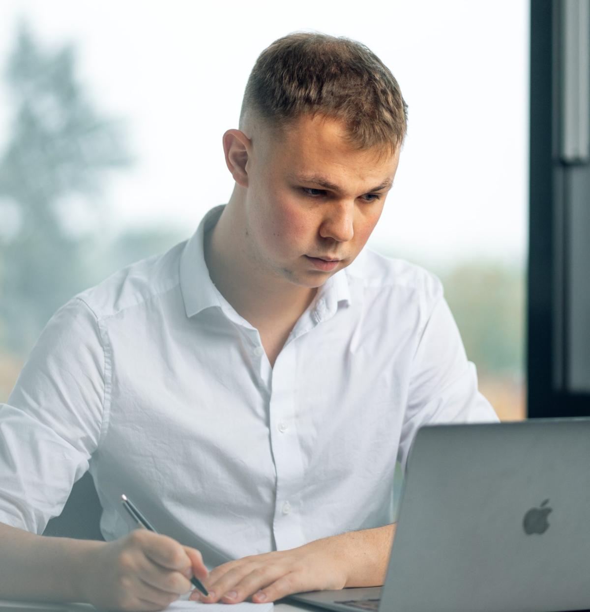 Junger Mann arbeitet konzentriert am Laptop, um die Kaltakquise zu verbessern.