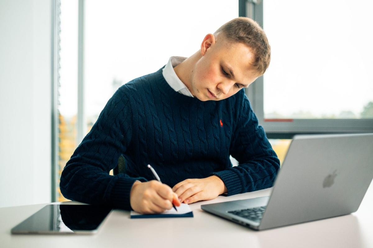 Mann schreibt Notizen zur Positionierung als Coach am Laptop.