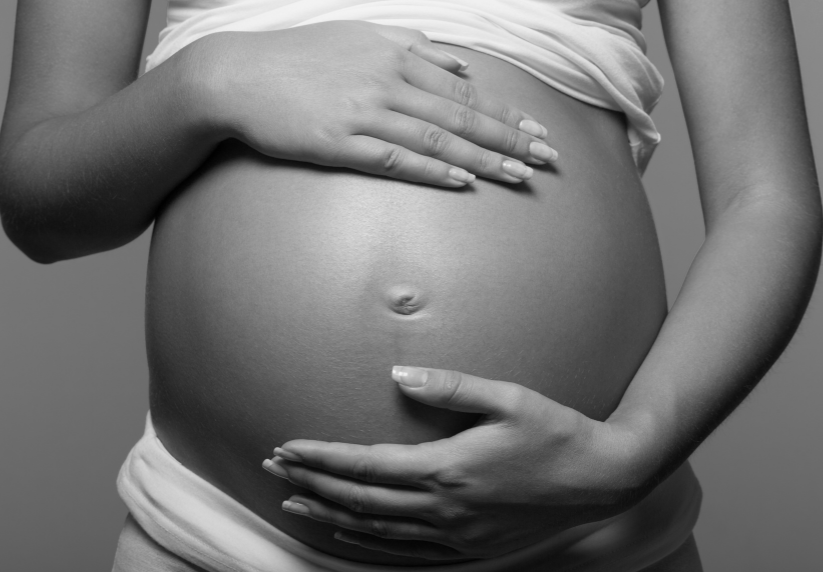 Schwangere Frau hält ihren Bauch und denkt über Gewicht nach der Schwangerschaft nach.