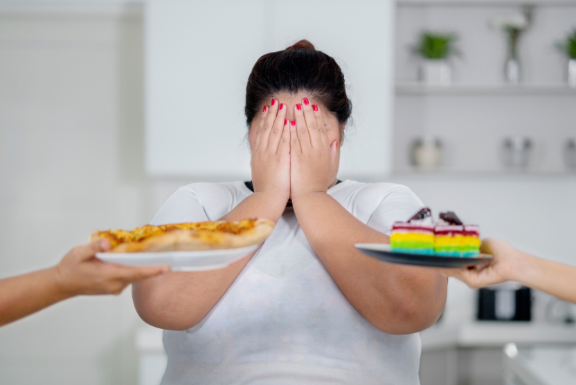 Eine Frau hält sich die Augen zu und ist mit Heißhunger konfrontiert.