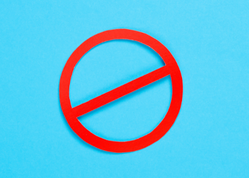Ein rotes Verbotsschild auf blauem Hintergrund symbolisiert den Verzicht beim Abnehmen mit Schokolade.