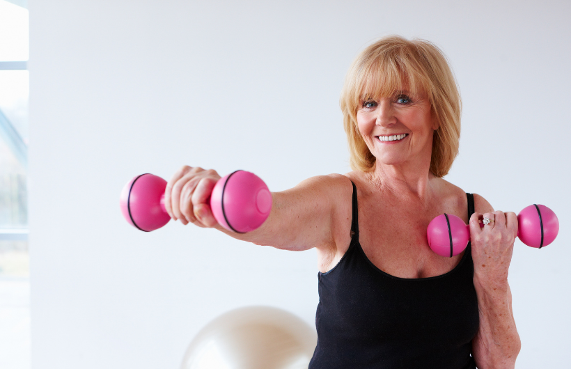 Eine Frau mit Hanteln beim Krafttraining in den Wechseljahren.