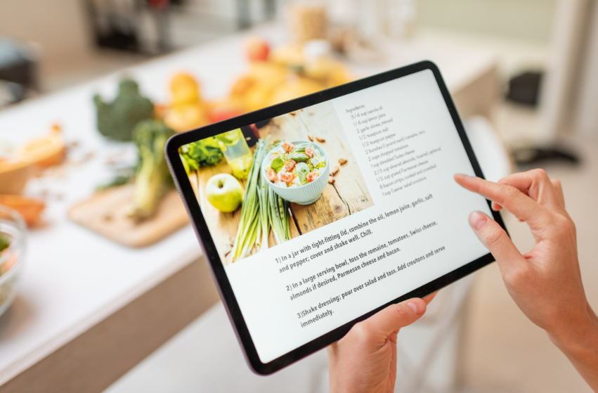 Eine Person liest ein Rezept für alltagstaugliche Mahlzeiten auf einem Tablet.