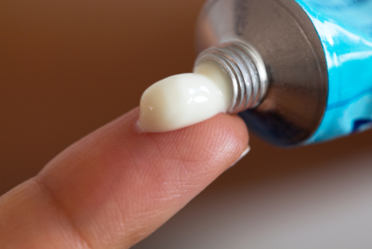 Eine Hand trägt eine Creme auf den Finger auf, um Cellulite loszuwerden.