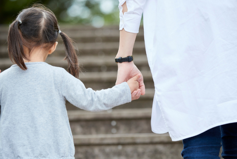 Eine Mutter und ihr Kind halten beim Treppensteigen Händchen, symbolisieren Familienernährung.