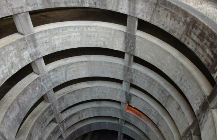 Detailansicht eines Betonbogens im Parkhaus mit kreisförmiger Struktur.