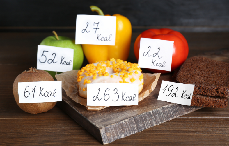 Vergleich von kalorienreichen Lebensmitteln mit Kalorienangaben auf kleinen Zetteln.