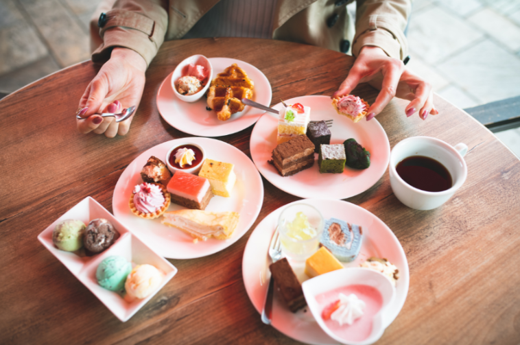 Eine Person sitzt am Tisch und genießt verschiedene Desserts und Kaffee.