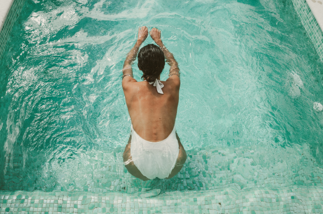 Eine Frau genießt ihren Luxusurlaub im Pool und entspannt dabei.
