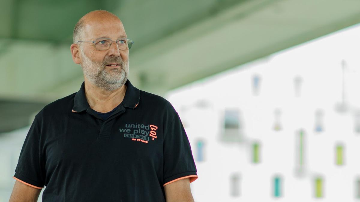 Ein Mitarbeiter im Einzelhandel in schwarzem Poloshirt steht vor einem hellen Gebäude; bKV-Leistungen sollen zum Arbeitsalltag passen.