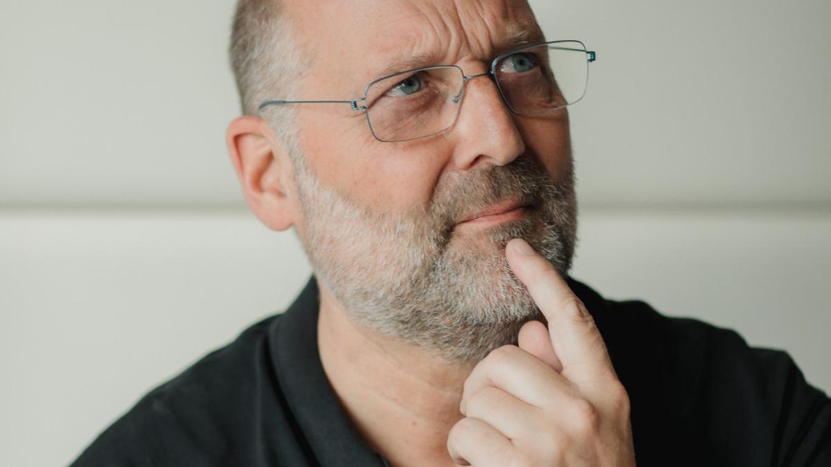 Ein nachdenklicher Geschäftsführer mit Brille berührt sein Kinn – bei der betrieblichen Krankenversicherung zählt der Nutzen.