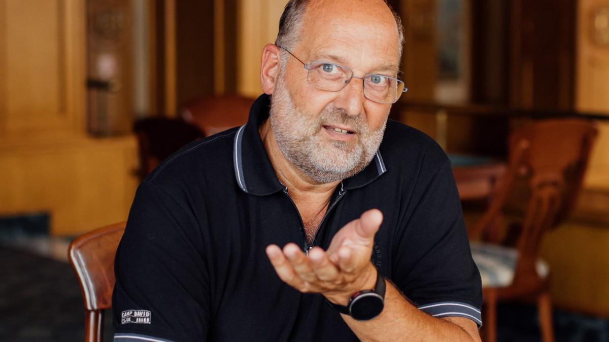 Ein Mann sitzt in einem Gastraum und gestikuliert im Gespräch über die betriebliche Krankenversicherung.