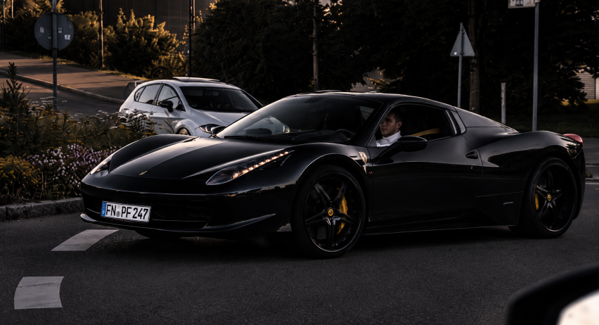 Ein schwarzer Ferrari 458 Italia fährt auf der Straße.