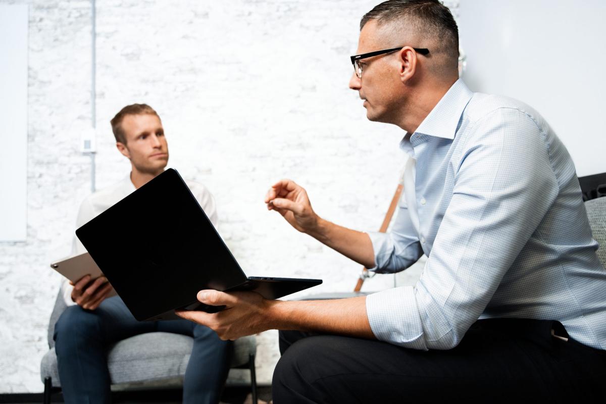 Zwei Personen diskutieren über Vertrieb und Umsatzsteigerung während eines Meetings.