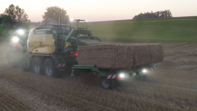 Moderne Ballensammelwagen eines Lohnunternehmers bei der Strohernte.