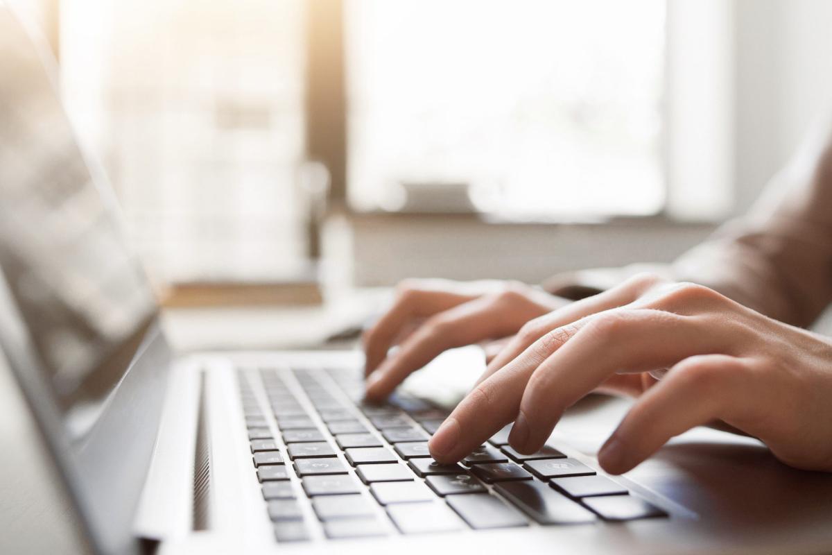 Hände, die auf einem Laptop tippen, während KI-Websites erstellt werden.